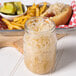 A jar of Silver Floss sauerkraut next to a hot dog and a plate of pickles.