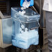 A person pouring ice into a blue Rubbermaid container.