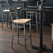 A Lancaster Table & Seating cross back bar stool with a natural wood seat.