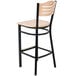 A Lancaster Table & Seating black bistro bar stool with a natural wood seat and back.
