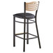 A Lancaster Table & Seating black wood bistro bar stool with a black cushioned seat and natural wood back.