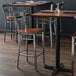 A Lancaster Table & Seating clear coat finish cross back bar stool with a wooden seat on a table in a restaurant.