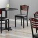 A Lancaster Table & Seating black bistro chair with a black vinyl seat and mahogany wood back.