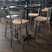 A Lancaster Table & Seating cross back bar stool with a natural wood seat on a table in a restaurant.