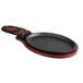 A Choice oval cast iron fajita skillet with a mahogany wood underliner and a red chili pepper handle cover.