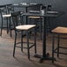 A Lancaster Table & Seating black cross back bar stool with a natural wood seat.