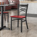 A Lancaster Table & Seating black metal chair with mahogany wood seat at a table in a restaurant.