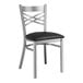 A Lancaster Table & Seating metal cross back chair with black vinyl cushion.