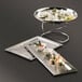 An American Metalcraft rectangle hammered stainless steel tray with food on a table.