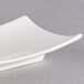 An Arcoroc rectangular porcelain plate with curved edges on a gray surface.