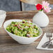 A close up of a bowl of broccoli salad in a white Acopa porcelain bowl.