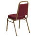 A burgundy Flash Furniture banquet chair with gold legs.