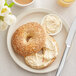 A plate with two bagels, one with Vegetable Cream Cheese spread and sesame seeds on it.