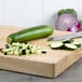 A medium green squash on a cutting board with a knife.