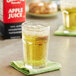 A glass of apple juice on a green napkin.