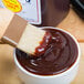 A brush dipping into a bowl of Sweet Baby Ray's barbecue sauce.