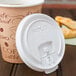 A Solo white plastic lid on a coffee cup with a pastry on a table.