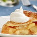 A slice of apple pie with Cool Whip on top.