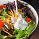 A bowl of vegetable salad with Ken's Buttermilk Ranch dressing on top.