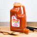 A Texas Pete 1 gallon jug of hot sauce on a cutting board.