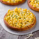 A small pizza with macaroni and cheese on a table with a Rich's par baked pizza crust.
