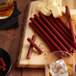 A wooden board with cheese and Weaver's Sweet and Spicy Snack Sticks.