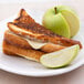 A grilled cheese sandwich with a slice of Great Lakes Swiss American Cheese and a green apple on a plate.