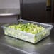 A Rubbermaid clear polycarbonate food storage box with lettuce in it.