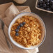 A bowl of Walnut Creek Amish Made Country Lane Granola with blueberries and a spoon on a table.