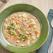 A white bowl of Spring Glen Fresh Foods ham and bean soup with vegetables and herbs.