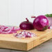 A close up of a Jumbo red onion on a cutting board with chopped onions.
