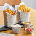 Two Acopa stainless steel containers filled with French fries and dipping sauce.