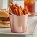 An Acopa stainless steel cup filled with French fries and a burger.