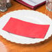 A red Hoffmaster paper dinner napkin on a white plate.