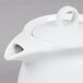 An Arcoroc white teapot with a lid and handle.