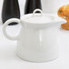 A white Arcoroc teapot with a lid.