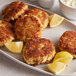 Crab cakes made with J.O. Crab Cake Mix on a plate with lemon wedges.