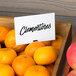 A pile of oranges with a mini chalk card that says "clementines" on the counter.