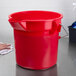 A Rubbermaid red bucket with a handle on a counter.