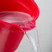 A red Rubbermaid BRUTE bucket filled with water pouring out.