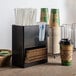 A black Choice countertop organizer with paper cups and straws.