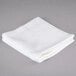 An Oxford Platinum white cotton washcloth with a twill border on a gray surface.