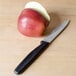 A Victorinox paring knife next to a red apple on a table.