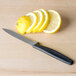 A Victorinox paring knife next to sliced lemons on a wooden table.