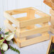 A wooden display riser with a wooden crate of flowers and bread.