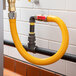 A yellow Regency gas connector hose with a red label connected to a pipe.