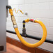 A yellow Regency gas hose connected to a pipe with black connectors.