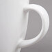A close-up of a Tuxton white china bistro mug with a handle.