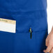 A person wearing a Chef Revival royal blue bib apron with a pen in the pocket.