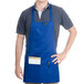 A man wearing a royal blue Chef Revival apron with a pocket.
